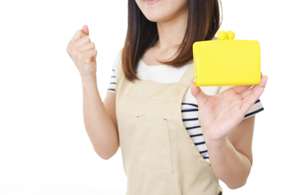 黄色い財布をもってガッツポーズをする女性