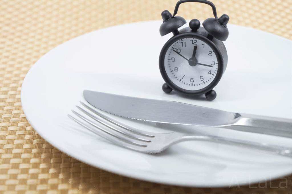 お皿と上に置かれた目覚まし時計とカトラリー